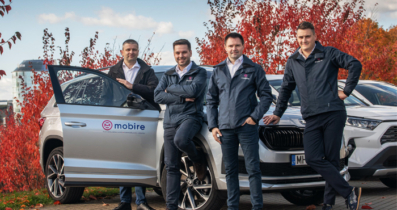 Four men in Mobire jackets standing next to a silver car with a Mobire logo, with red autumn trees in the background.