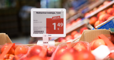 An electronic price tag displaying a special offer for nectarines in a store. The price is shown as 1.49 euros per unit, with the word 'AKCIJA' (meaning 'special offer' in Lithuanian) highlighted in red. Nectarines are visible in red netted bags surrounding the price tag.