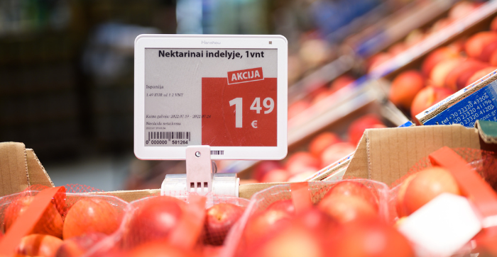 An electronic price tag displaying a special offer for nectarines in a store. The price is shown as 1.49 euros per unit, with the word 'AKCIJA' (meaning 'special offer' in Lithuanian) highlighted in red. Nectarines are visible in red netted bags surrounding the price tag.